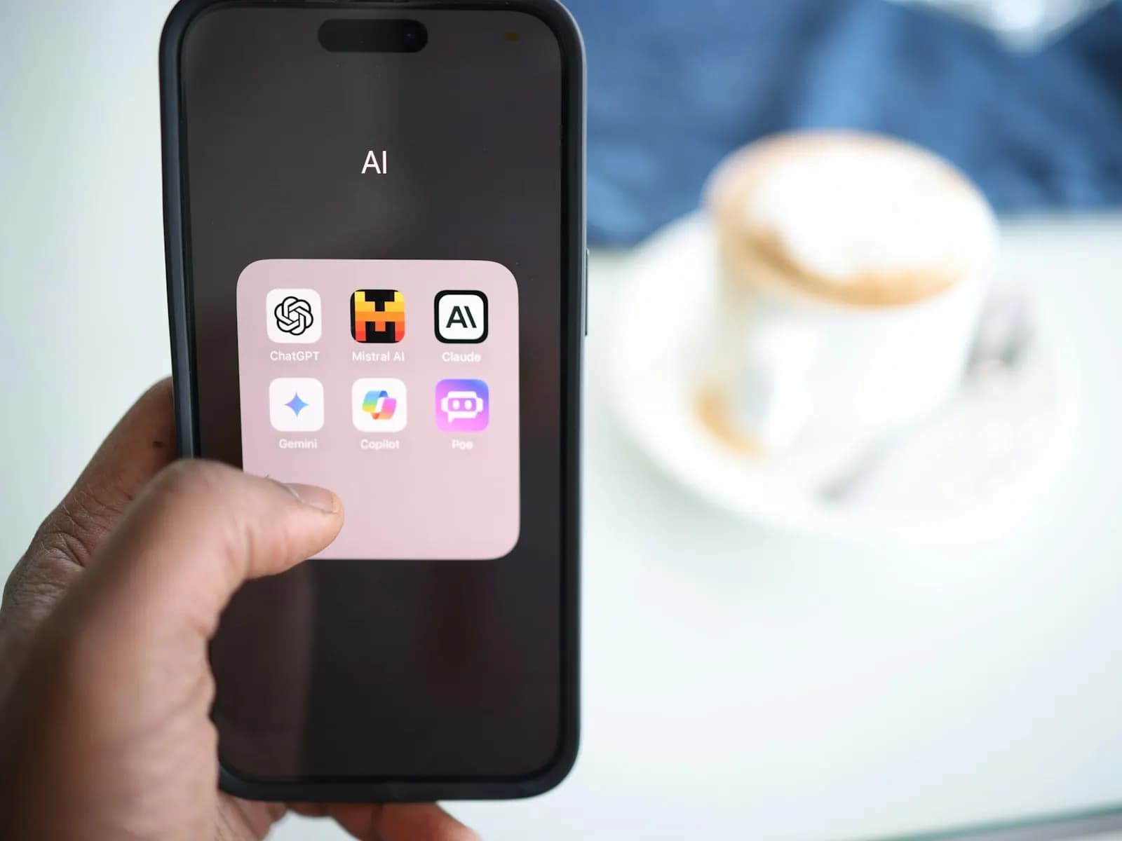 Telefon z aplikacjami asystentów AI trzymany w dłoni