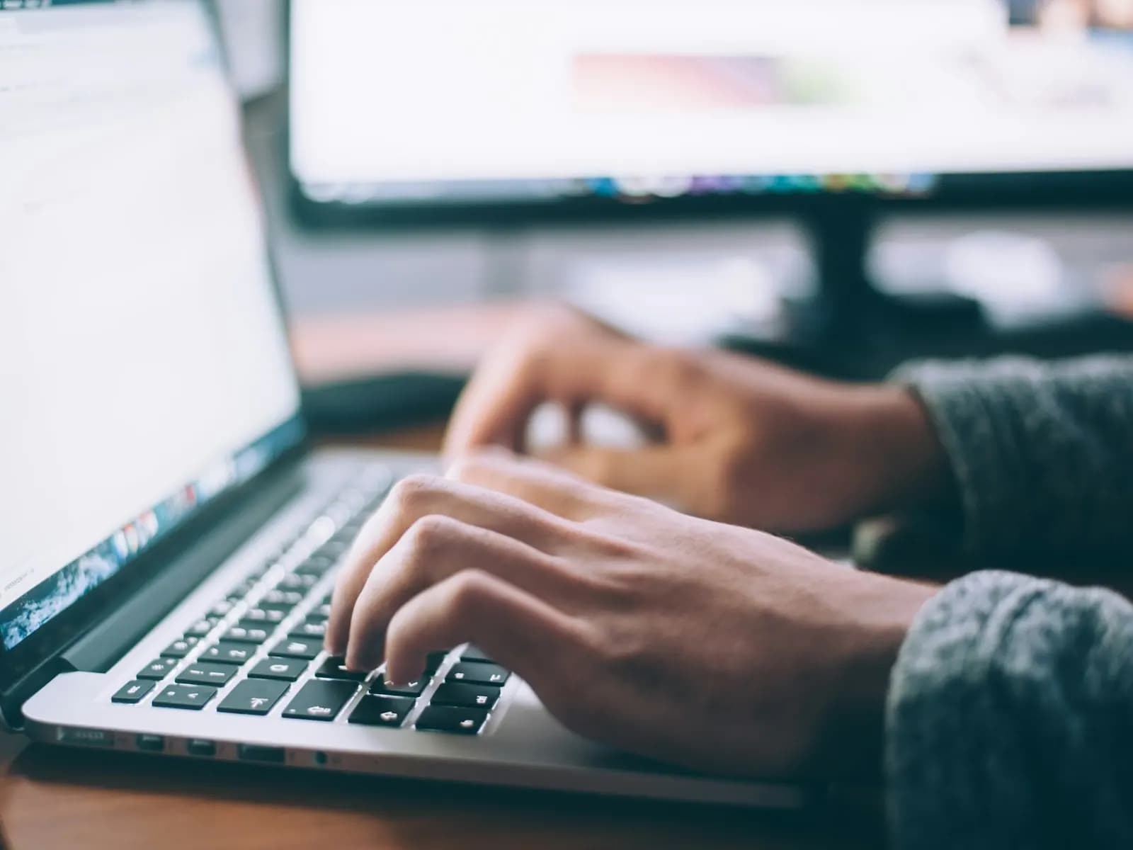 Dłonie na klawiaturze laptopa podczas pracy nad stroną internetową
